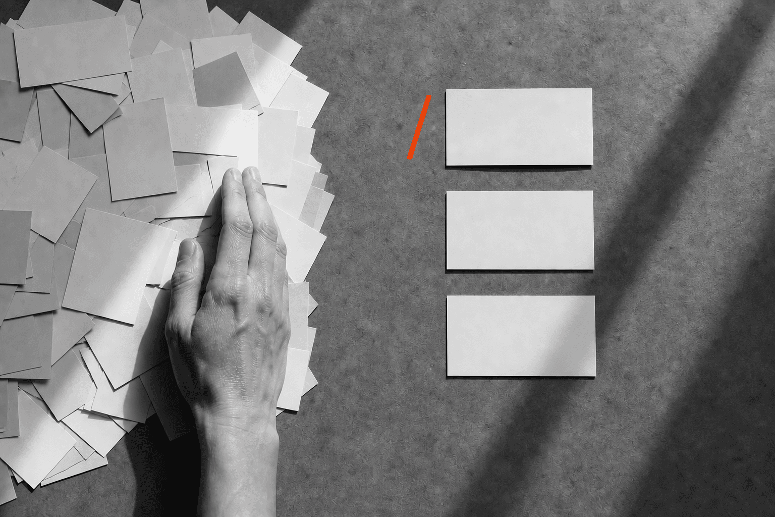 A hand separates three task cards from a crowded pile, with a vivid red slash beside the first card